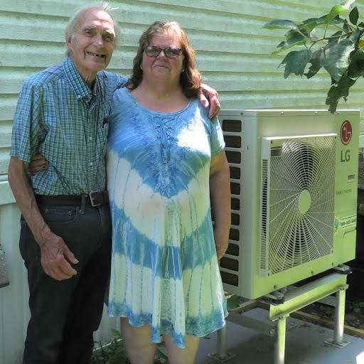 A man and a woman stand beside a heat pump unit.
