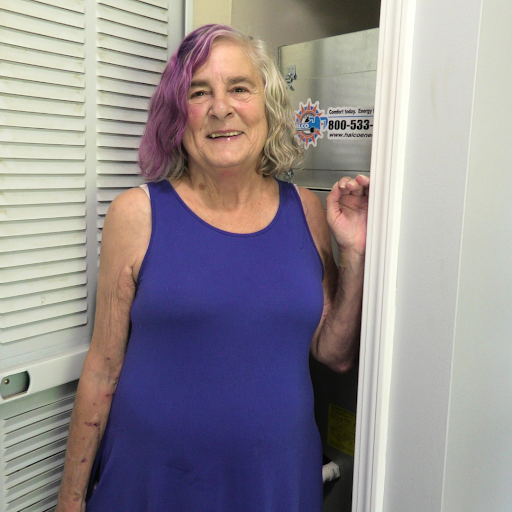 A woman stands next to a heat pump installation.