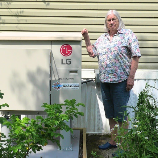 A woman stands in front of an outdoor heat pump unit.